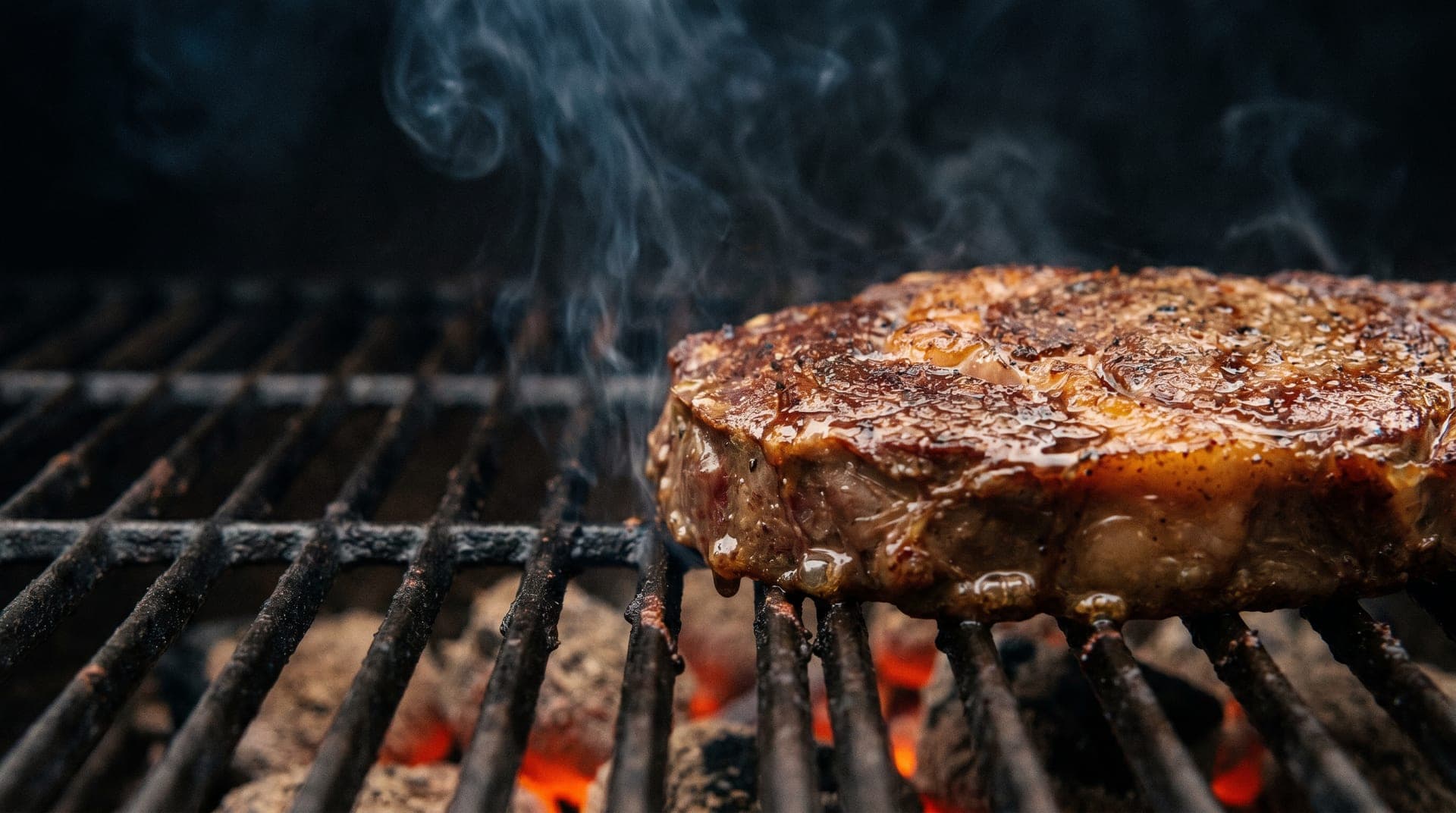 Premium Ribeye Steak auf glühender Holzkohle — atmosphärisches Hero-Bild für Fleischthermometer-Test 2026