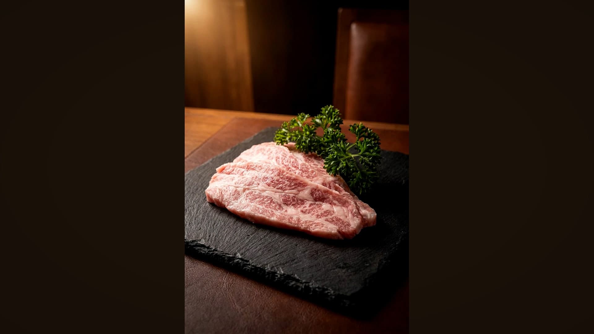 Flacher, stark marmorierter Secreto-Cut vom Iberico-Schwein auf dunklem Schiefer — KI-generiertes Symbolbild